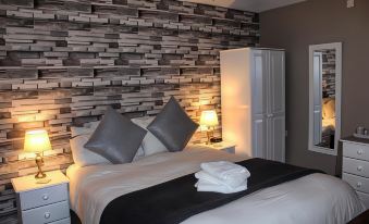 a bed with a gray blanket and white sheets is in a room with brick wall paneling at The Mary Tavy Inn