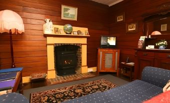 a cozy living room with a fireplace , wooden walls , and a blue couch near the tv at Westbury Gingerbread Cottages