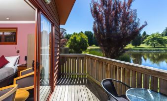 a wooden deck with a table and chairs , overlooking a lake and trees , under a clear blue sky at Aspect Tamar Valley Resort