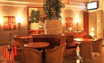 a modern , well - lit restaurant with wooden tables and chairs , large potted plants , and comfortable seating arrangements at Hotel Woodland