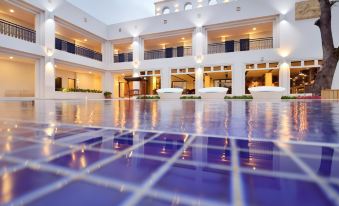 a large white building with multiple floors , balconies , and a pool area with a blue tiled floor at J Resort