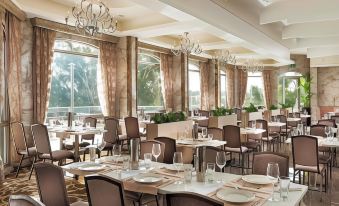 a large , well - lit dining room with multiple tables and chairs arranged for a group of people at Swan River Hotel