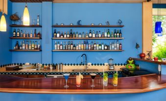 a bar with a blue wall , shelves of bottles , and various drinks on the counter at Boutique Hotel Luna Azul