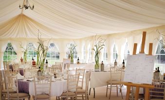a large white tent with tables and chairs set up for a wedding reception , possibly at a church at Lovelady Shield Country House Hotel
