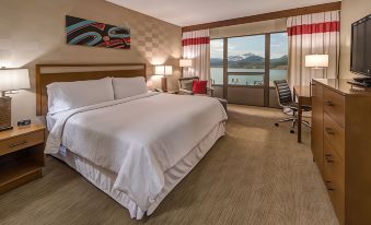 a hotel room with a large bed , a desk , and a window overlooking a body of water at Four Points by Sheraton Juneau