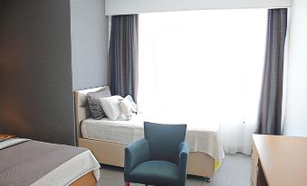 a modern bedroom with a bed , chair , and window , along with a small table and lamp at Port Marina Hotel