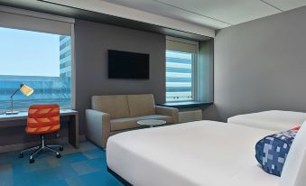 a modern hotel room with a bed , couch , and tv , as well as a small tv on the wall at Aloft Richardson