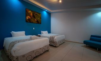 a modern hotel room with two beds , blue walls , and a painting on the wall at Hotel Quelitales