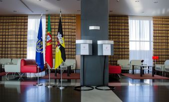 a modern office lobby with multiple flags , including the flag of the republic of angola , flags of germany , and three - color designs , surrounded at VIP Executive Santa Iria Hotel