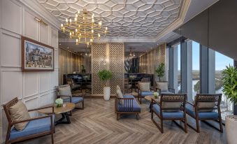 a modern lounge area with wooden floors , chairs , and tables , as well as a chandelier hanging from the ceiling at Melia Vinpearl Hue