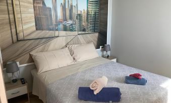 a cozy bedroom with a large window showing a city skyline , and a bed with folded towels on it at The Lux