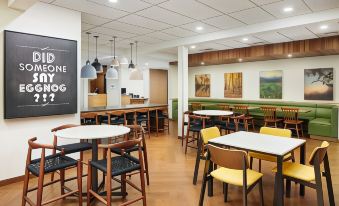 "a modern café with wooden tables and chairs , a bar area , and a sign that says "" dine for "" on the wall" at Fairfield Inn & Suites Worcester Auburn