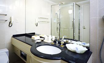 a bathroom with a glass shower , black countertop , and white sink , set against a backdrop of white walls at IMABARI KOKUSAI HOTEL