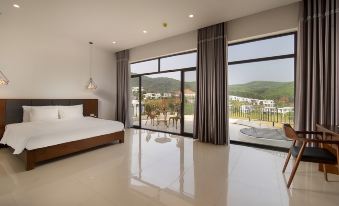 a modern bedroom with a large bed and sliding glass doors leading to a balcony overlooking the mountains at Ivory Villas & Resort