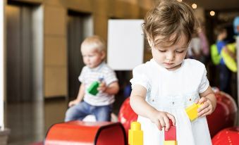 a young girl and a young boy are playing with wooden blocks in a room at Novotel Montréal Centre