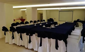 a conference room set up for a meeting , with tables covered in black tablecloths and chairs arranged around them at Seven Days Hotel