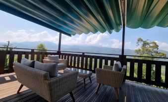 a wooden deck with a table and chairs , surrounded by mountains and a view of the water at Hotel Cerro La Nina