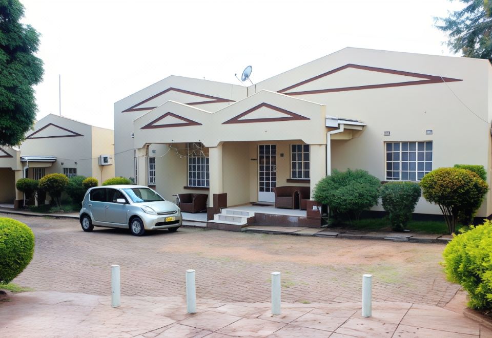 a car is parked in front of a house with a driveway and brick pillars at Riverside Apartments