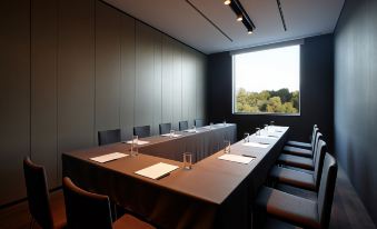 a long table with multiple chairs and white papers is set up in a conference room at Shilla Stay Dongtan