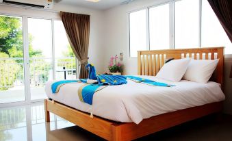 a large bed with a wooden headboard and white sheets is in a room with a window at That Phanom River View Hotel