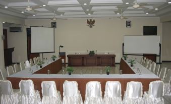 a conference room set up for a meeting , with chairs arranged in a semicircle around a long table at Front One Resort Magelang