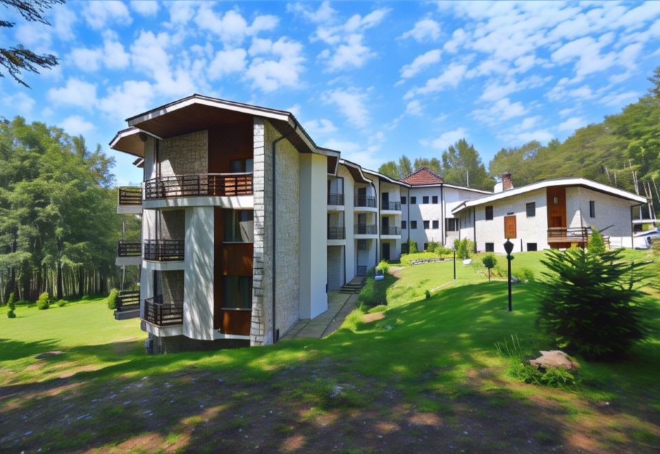 a modern building with multiple balconies and a large courtyard , surrounded by lush greenery and trees at Hotel Edelweiss