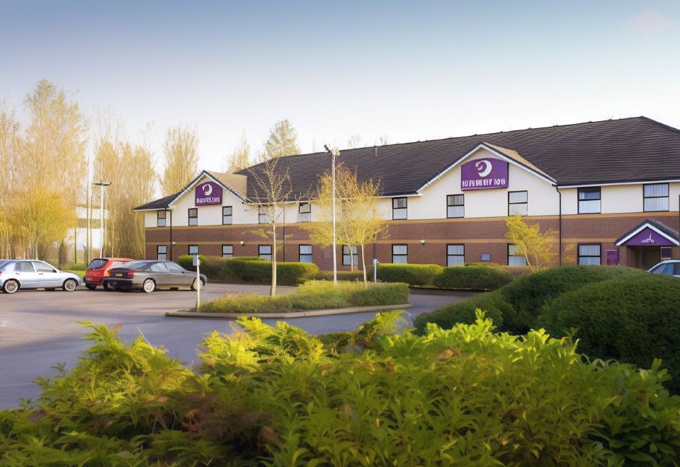 a holiday inn express hotel with a purple sign and a car parked in front at Premier Inn Liverpool (Tarbock)