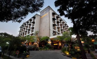 a large hotel building surrounded by lush greenery , with a fountain in front of it at Amaroossa Hotel Bandung Indonesia