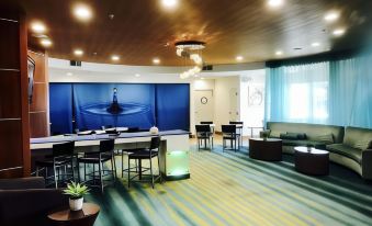 a large , brightly lit room with a blue mural on the wall and several tables and chairs arranged for meetings or events at SpringHill Suites Madera