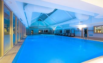 an indoor swimming pool surrounded by white walls , with a blue tiled floor and ceiling at The Park Royal Hotel & Spa