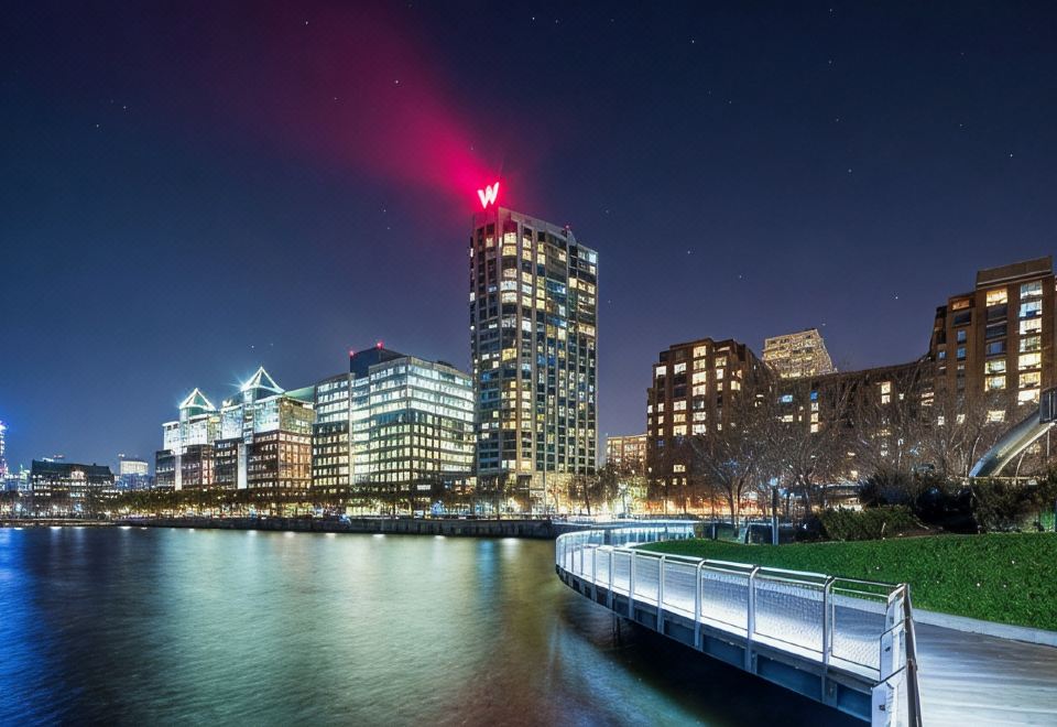 a city skyline at night , with tall buildings illuminated and a boat dock in the foreground at W Hoboken