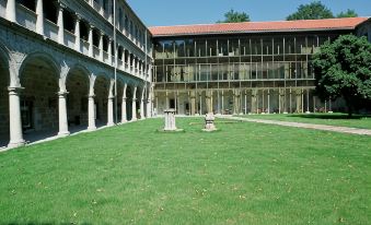 a courtyard with a building on one side and a courtyard on the other , surrounded by green grass at Parador de Santo Estevo