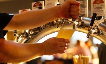 a person is pouring a beer from a tap into a glass , with multiple beer taps and bottles in the background at The Marina Hotel - Mindarie