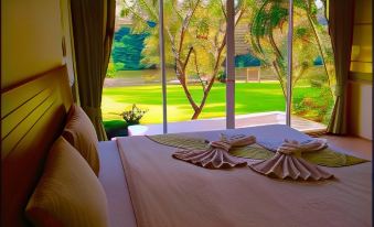 a bed with a pink and white blanket is shown in front of a window at Vimannam Resort