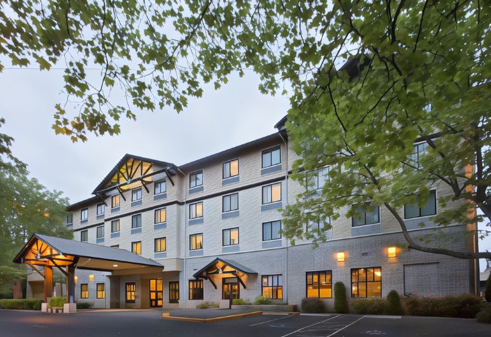 a large , modern hotel building with multiple floors and balconies , situated next to a parking lot at The Inn at GIG Harbor