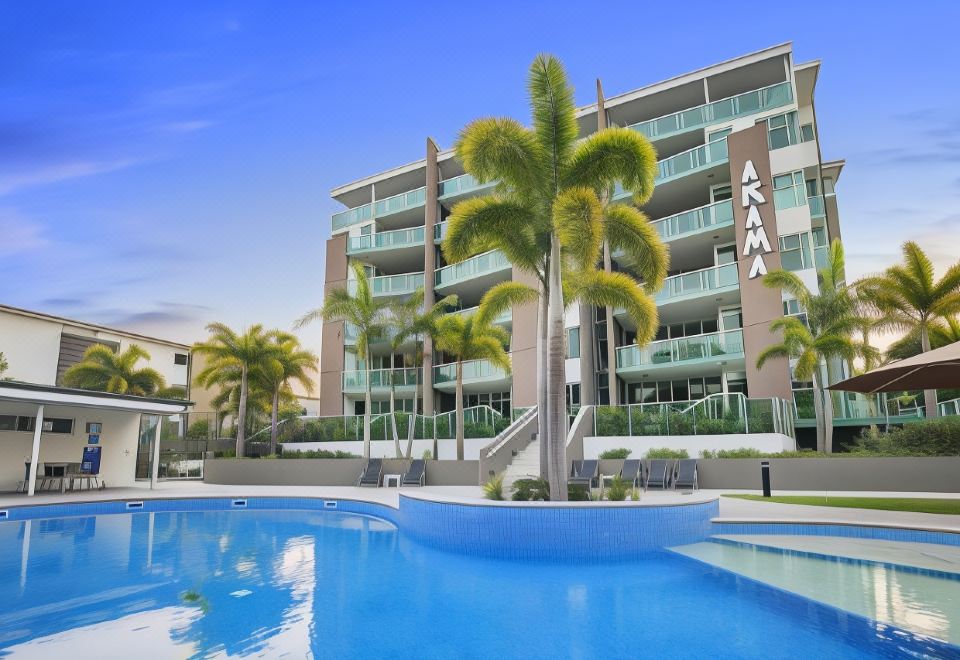 a large apartment building with a swimming pool in front of it , surrounded by palm trees at Akama Resort