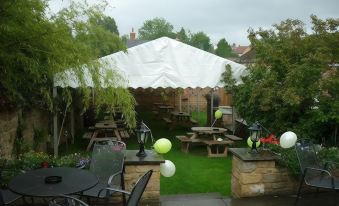 a white tent set up in a grassy yard , providing shade and protection from the rain at The Brewers Arms