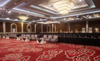 a large conference room with multiple rows of chairs arranged in a semicircle , creating a formal setting for a meeting or event at The Rich Jogja Hotel