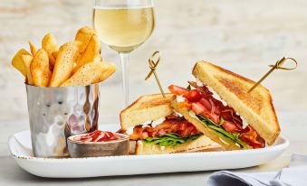 a plate with a sandwich , french fries , and a glass of wine on a table at Courtyard Danbury
