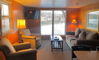 a cozy living room with wooden walls , large windows offering views of the outdoors , and comfortable furniture at Point View Resort