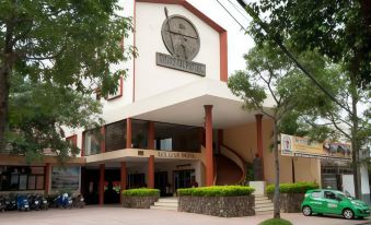 a modern building with a clock on the front , surrounded by trees and cars parked outside at DAM San Hotel