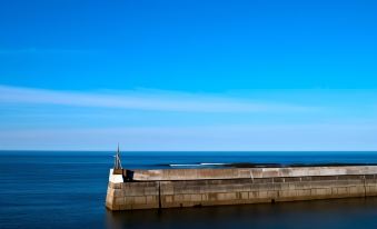 a long pier extending into the ocean , with a small flag on the right side at Purdy Lodge