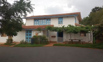 a two - story house with a red tile roof and blue doors is surrounded by greenery at Casa de la Piedra