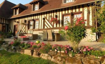 a large house with a red roof and windows is surrounded by a well - maintained garden at Le Pressoir