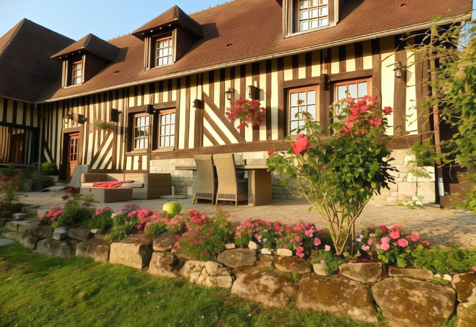 a large house with a red roof and windows is surrounded by a well - maintained garden at Le Pressoir