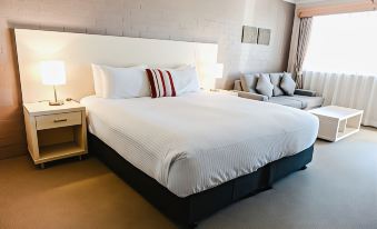 a large bed with white linens and a black headboard is in a hotel room at Balan Village Motel