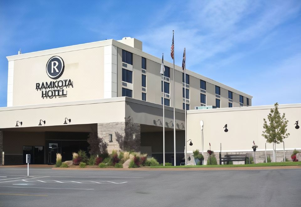 "a large hotel building with the name "" ramkota hotel "" prominently displayed on its facade , surrounded by other buildings and a parking lot" at Bismarck Hotel and Conference Center