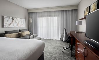 a modern hotel room with a bed , couch , desk , and window curtains , along with a tv and other amenities at Courtyard Lincroft Red Bank