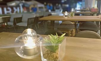 a dining table with a glass vase containing a small plant , candle , and two glasses at Chaisaeng Palace Hotel