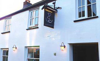 "a white building with a sign for "" 2 3 "", an english restaurant , and two lanterns on either side of the entrance" at The Anchor Inn